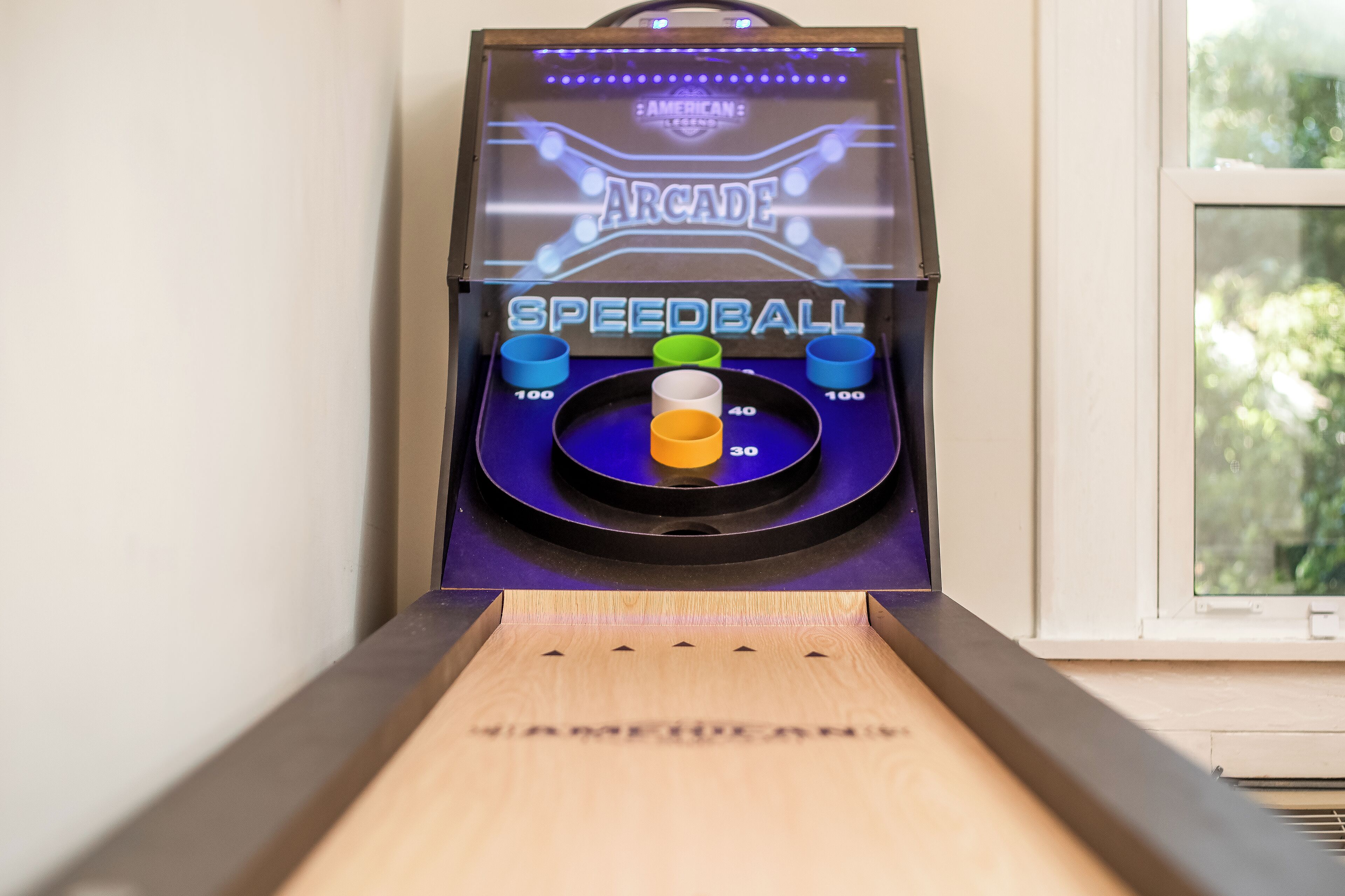 En Speedball arkademaskine med en træbase og et vindue i baggrunden.