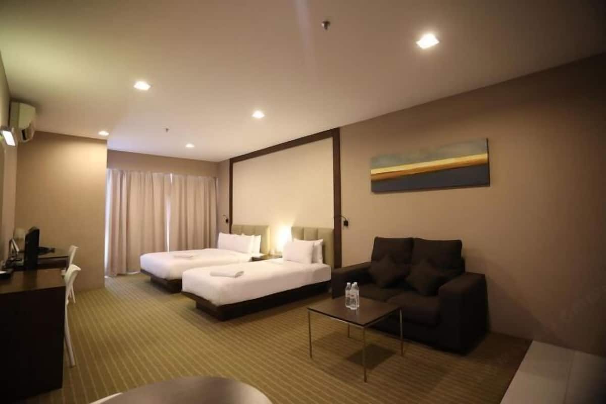 A hotel room with two beds, a desk, a sofa, and a painting on the wall.