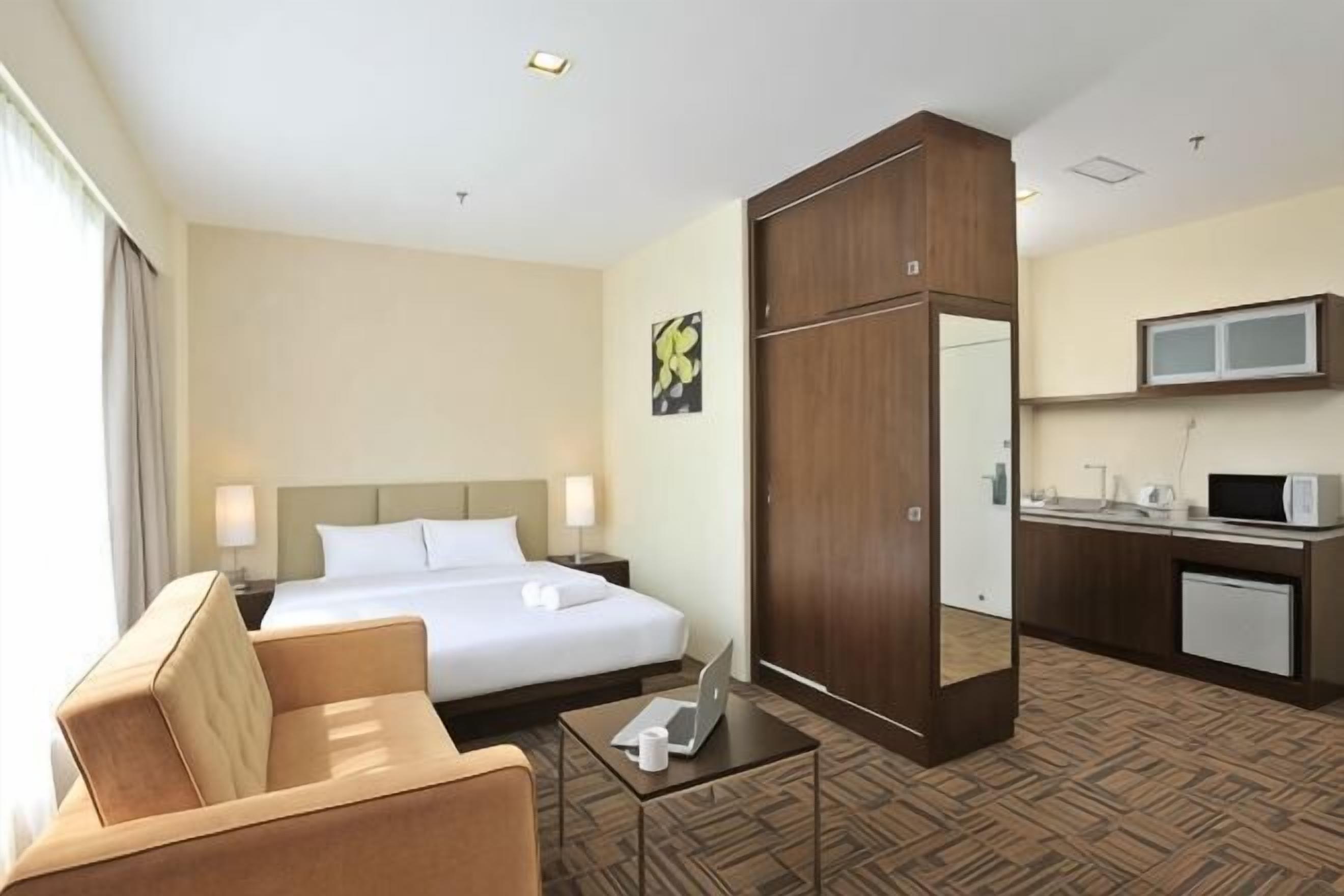A hotel room with a bed, a desk, a chair, a TV, and a mirror.