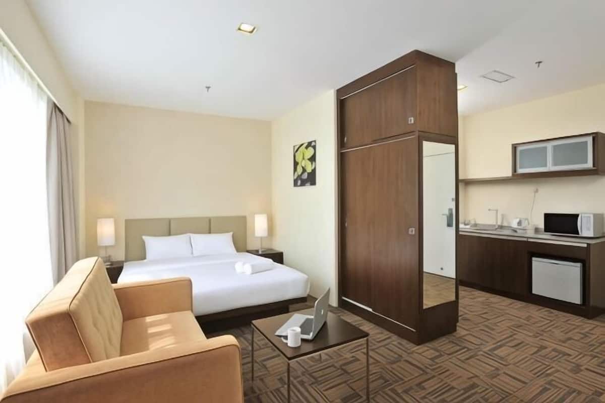 A hotel room with a bed, a desk, a chair, a TV, and a mirror.