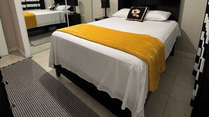 A hotel room with a bed, bedside tables, a mirror, and a ceiling light. - The Brompton's Luxury Apt (Kingston)