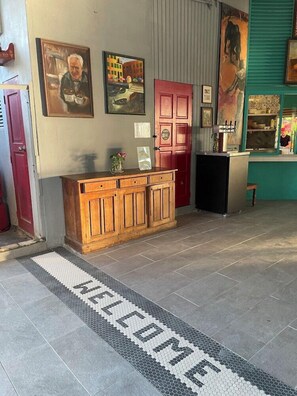 A reception area with a wooden counter, a red door, and a welcome mat.