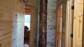 Ein Innenraumflur mit Holzwänden, einer großen zentralen Säule und einer Tür auf der rechten Seite.