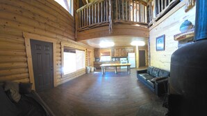 Ein Blockhaus-Interieur mit Holzboden, einem Essbereich, einer Couch und einem großen Wassertank.