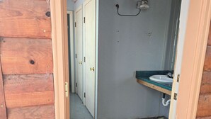 A narrow hallway with wooden walls and a door leading to a bathroom with a sink and mirror.