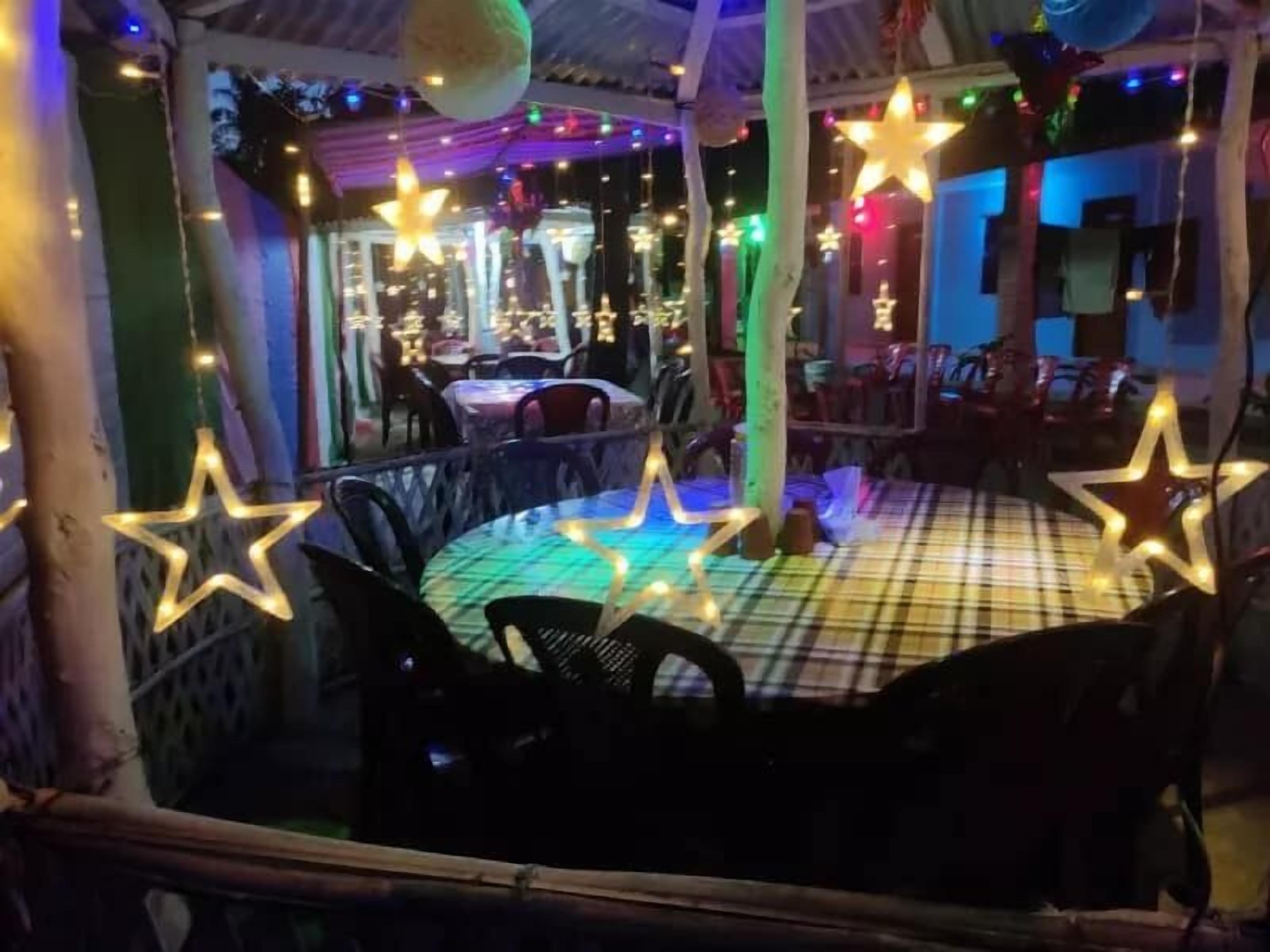 An outdoor seating area with tables and chairs, decorated with star-shaped lights and colorful string lights.