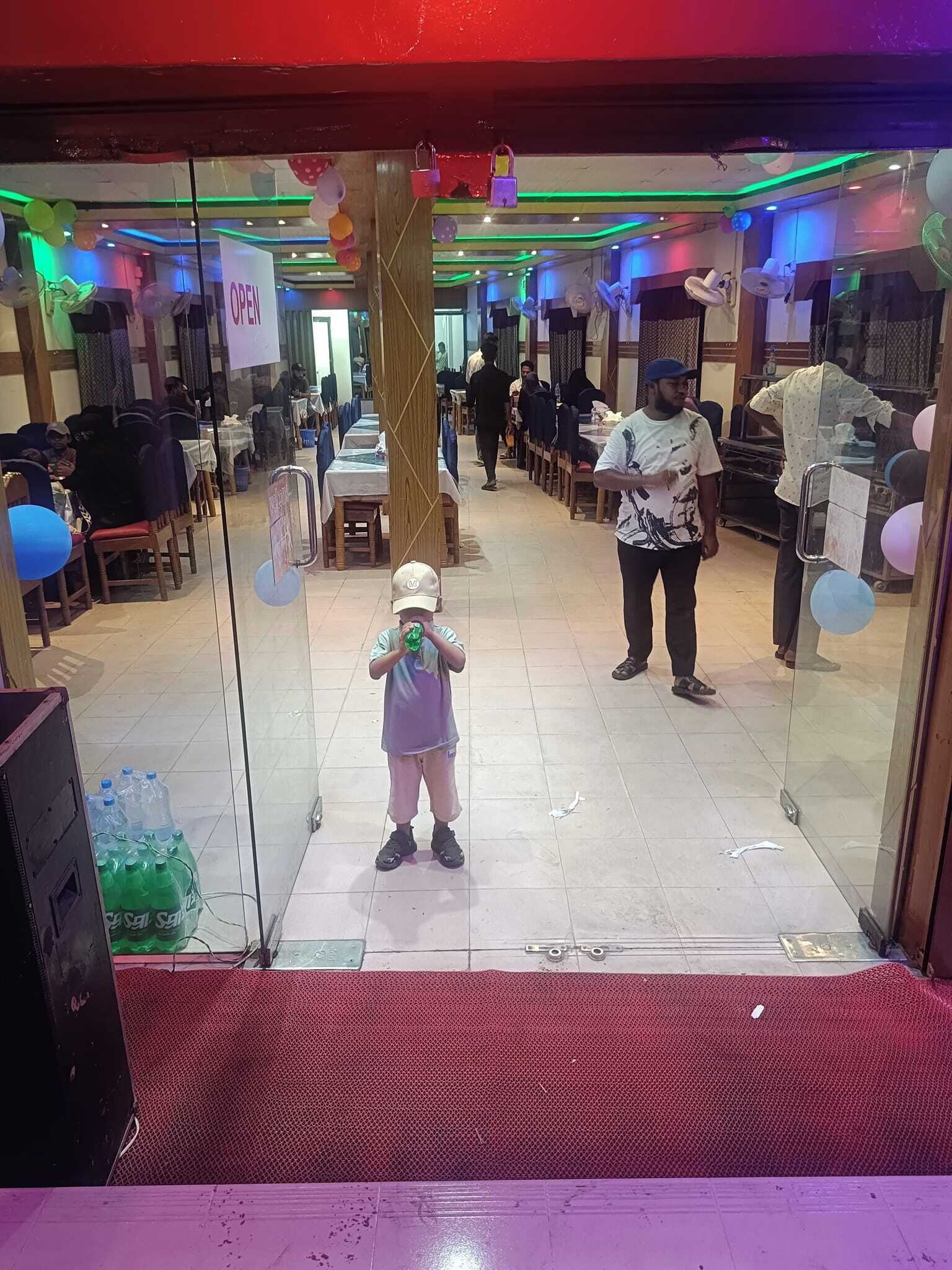 Un restaurante con mesas en el interior, entrada de vidrio y globos.