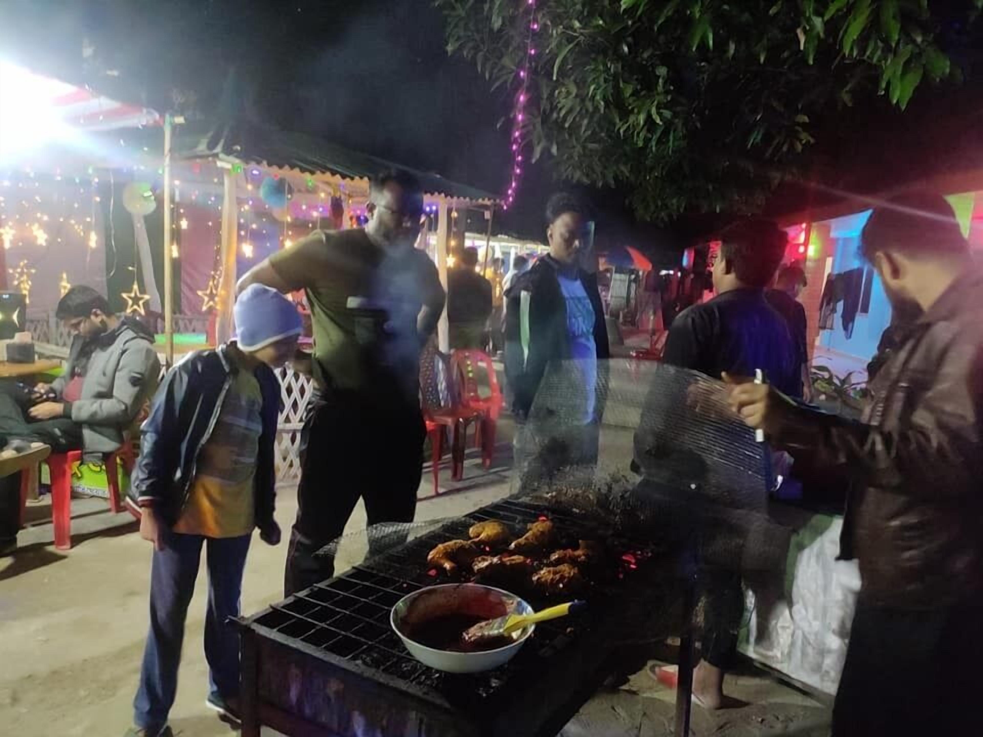 Un barbecue installé, avec des personnes rassemblées autour.
