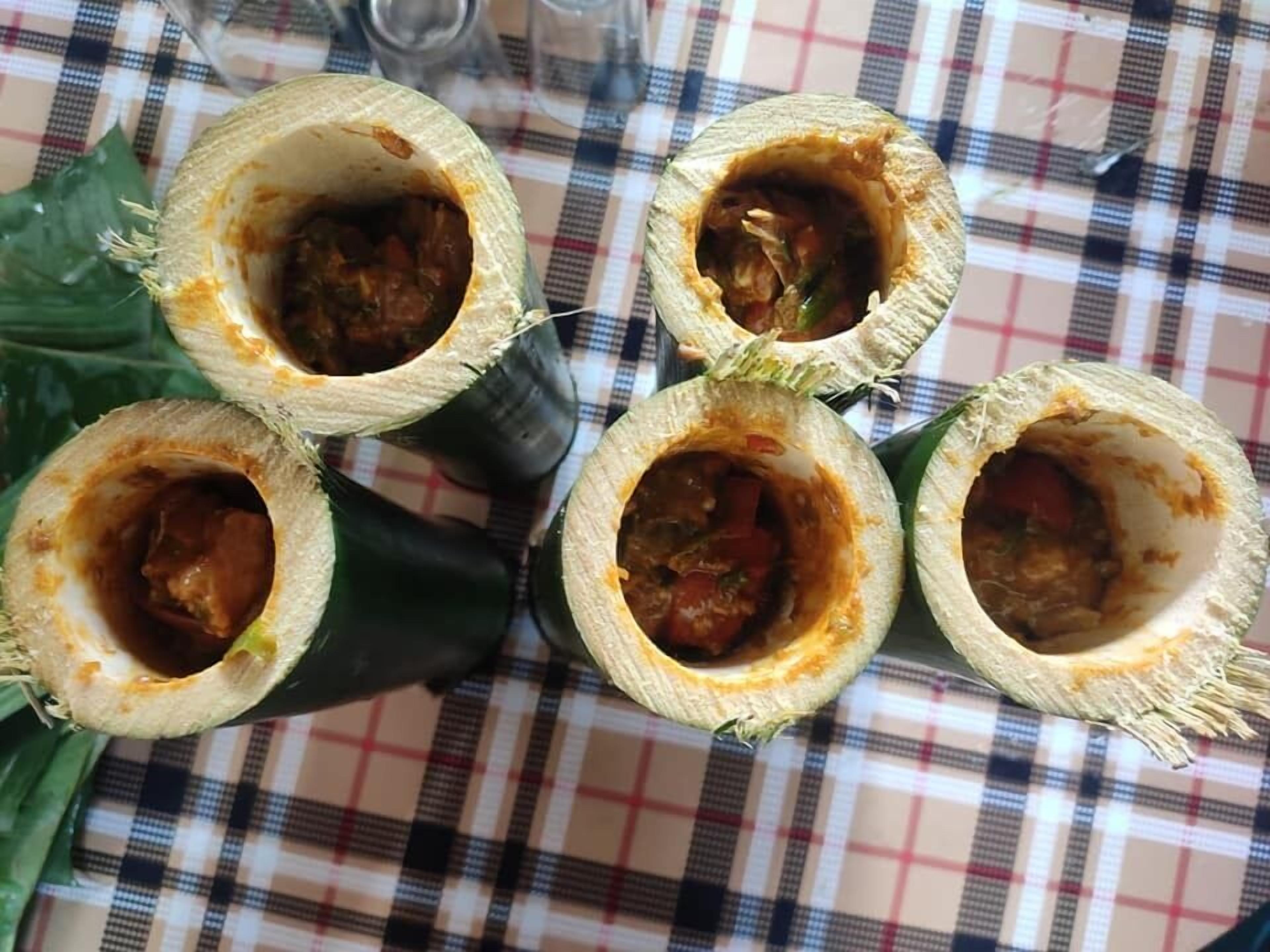 A table with five burritos on a checkered tablecloth.