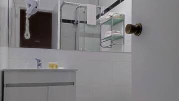 A bathroom with a toilet, a sink with a mirror above it, and a towel rack with towels.