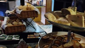 Uma mesa de buffet com diversos pães e um frasco de mel.