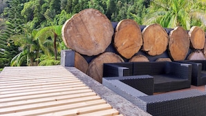 Eine Holzterrasse mit Holzscheiten und Gartenmöbeln.