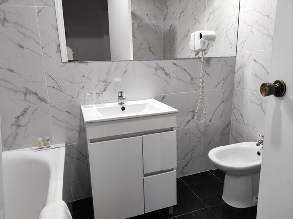 A bathroom with a white sink, mirror, and toilet.