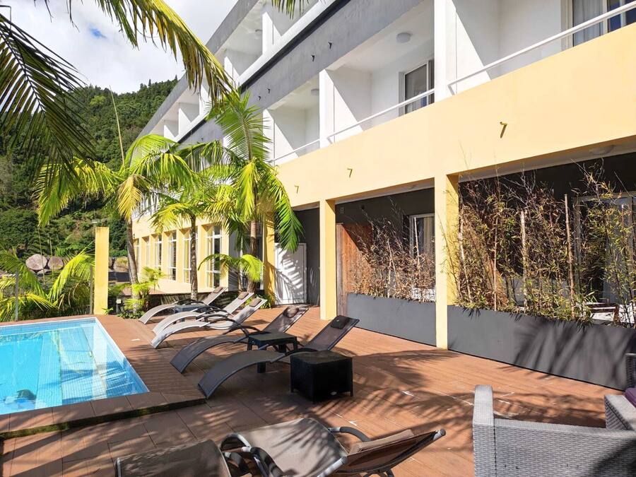 A poolside area with lounge chairs, a swimming pool, and a building with balconies.