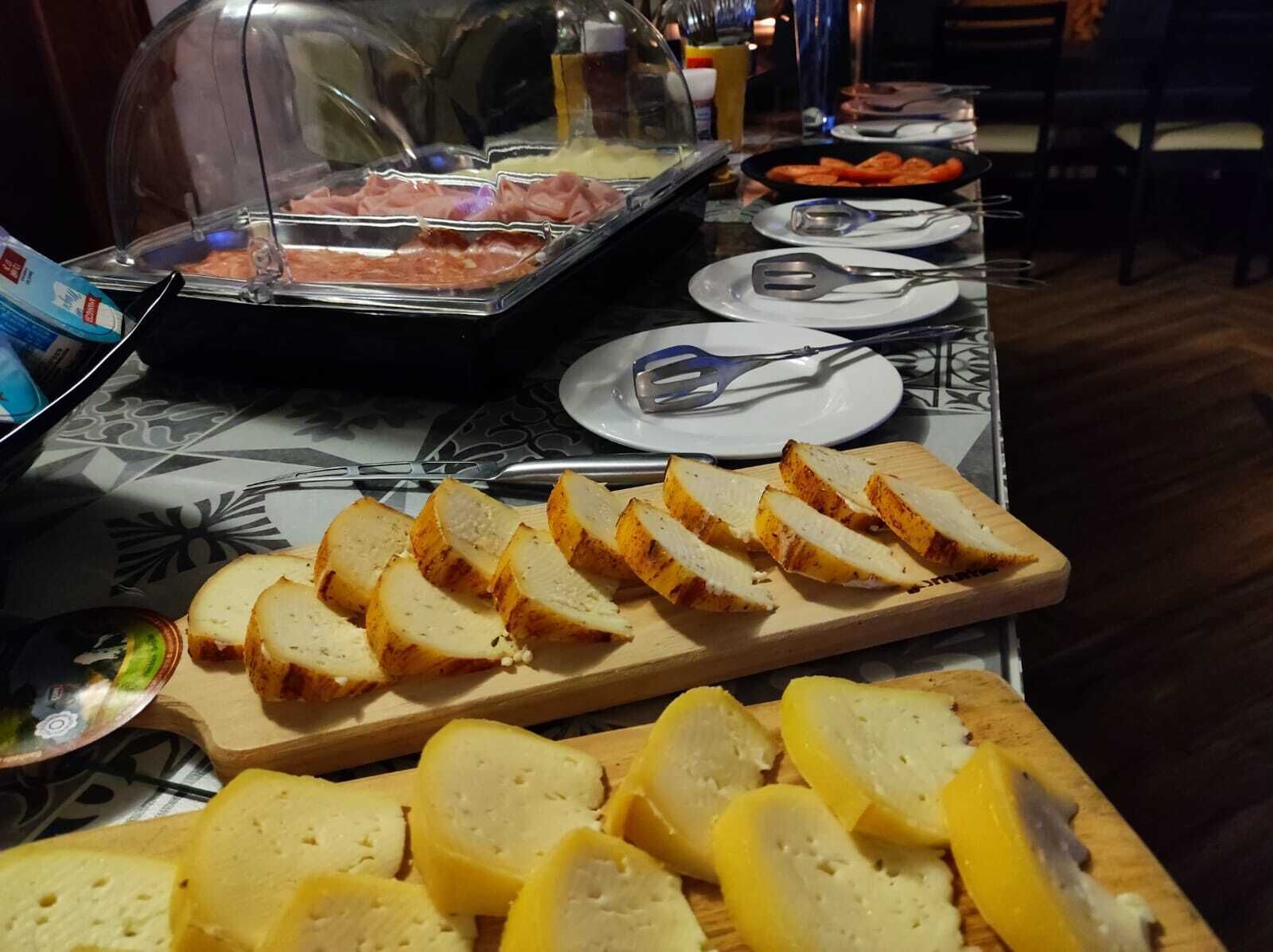 A buffet table with sliced bread, a meat tray, and plates with utensils.