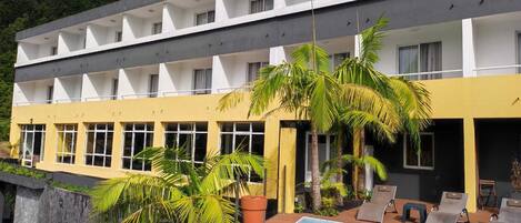 Un hôtel doté d’une piscine, de plusieurs balcons et de palmiers.