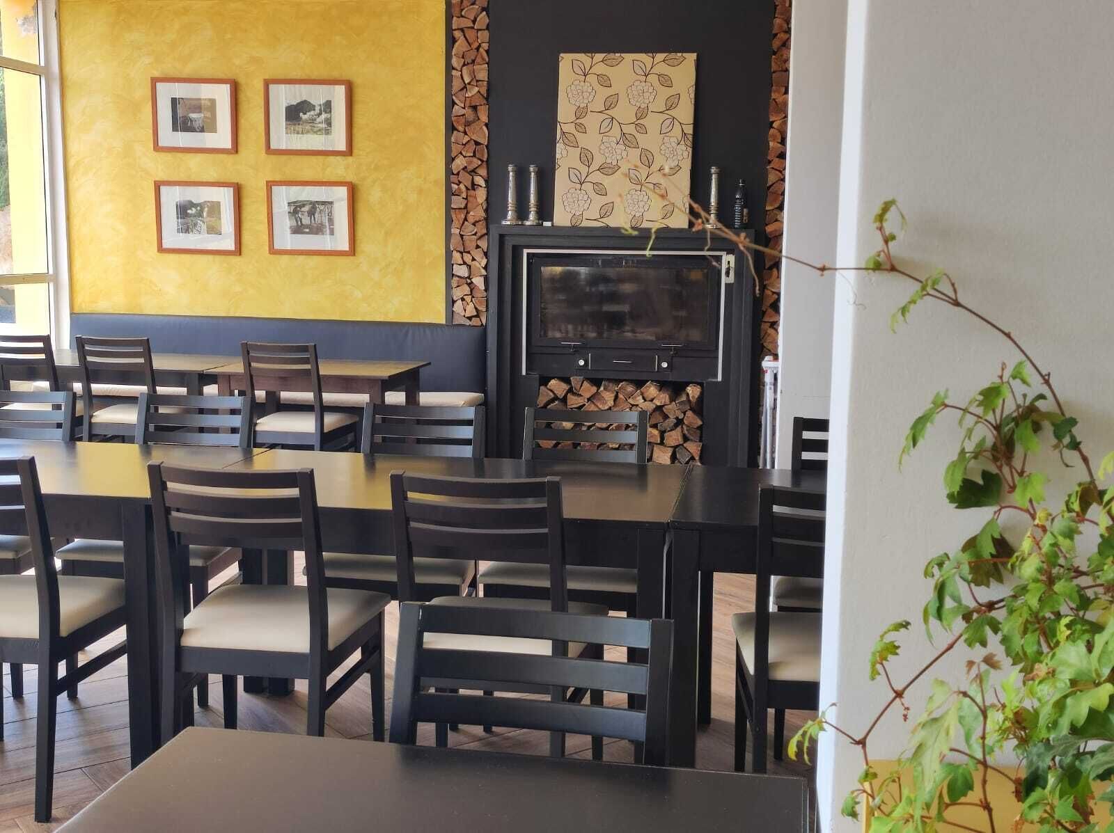 Een restaurant met een zwart televisiescherm, ingelijste foto's aan de muur en een open haard met hout.