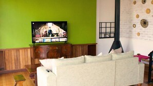 A living room with a green wall, wooden furniture, a sofa, and a flat-screen TV.