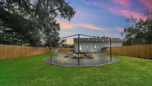 A backyard with a wooden fence, a fire pit, and a hammock.