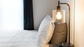 A modern hotel room with a bed, a nightstand, and a lamp with a visible light bulb.