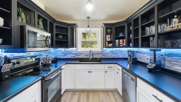 A modern kitchen with dark cabinetry, a blue countertop, and a built-in oven.