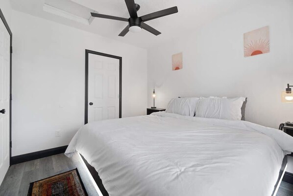 Un dormitorio con una cama grande, un ventilador de techo, una puerta y luces fijadas a la pared.