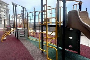 Un parque infantil con varios juegos, incluyendo un tobogán, estructuras para escalar y una barra de monos.