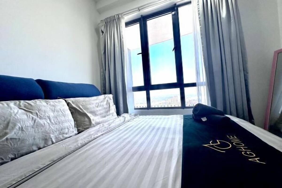Una habitación de hotel con cama, ventana con cortinas y vista a la ciudad.