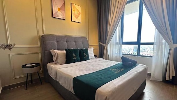 Ein Hotelzimmer mit einem großen Bett, einem Nachttisch, einem Fenster mit Vorhängen und Blick auf die Stadt.
