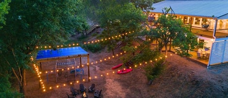 Eine Außenpatio-Terrasse mit überdachter Sitzgruppe, Lichterketten und einem Feuerkorb.