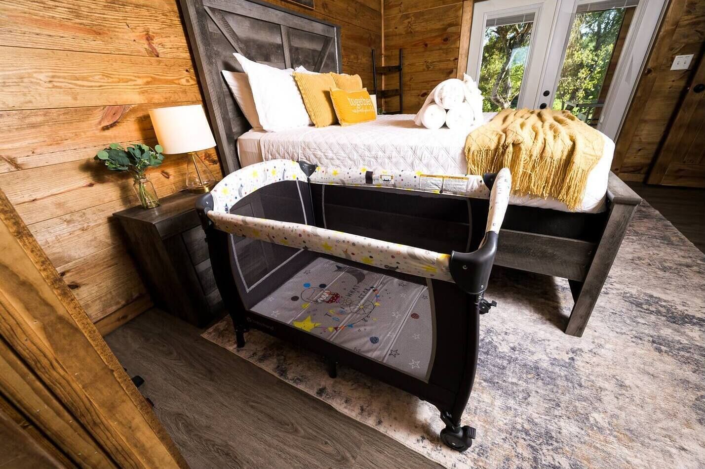Una habitación acogedora con una cama, una cuna para bebé y una ventana.