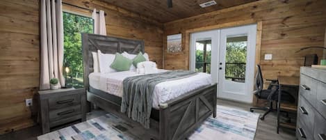 A wooden cabin bedroom with a bed, nightstands, a desk, and a ceiling fan.