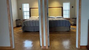 Un dormitorio con una cama grande, dos mesitas de noche y una ventana con persianas.