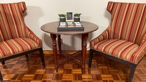 Dos sillones a rayas, una mesa redonda de madera con un letrero y un suelo de madera con dibujo de espiga.