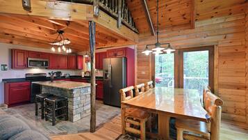 A log cabin interior with a kitchen, dining area, and a stone island.