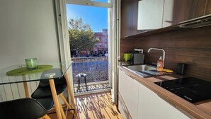 A compact kitchen with a balcony, a small dining area, and a view of the cityscape.