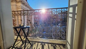A balcony with a metal railing, a small table, and a view of buildings in the background.