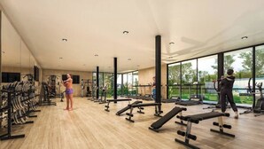 Une salle de sport spacieuse, dotée de divers appareils d’exercice, de grandes fenêtres et d  ’un plancher en bois.
