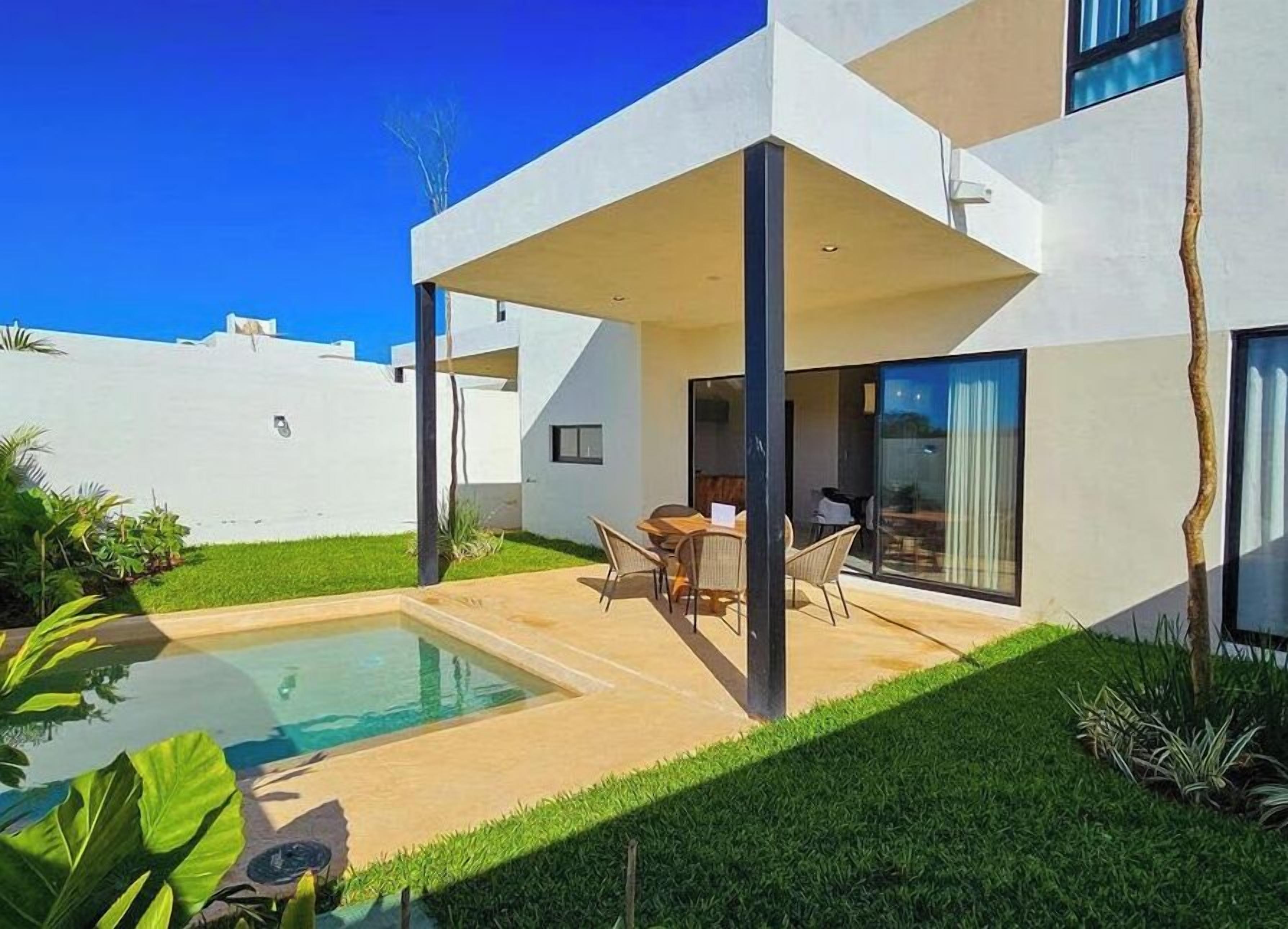A modern house with a swimming pool, outdoor seating, and a well-maintained lawn.