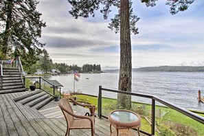 Relax on the deck with a serene lake view, surrounded by lush greenery and a distant shoreline.