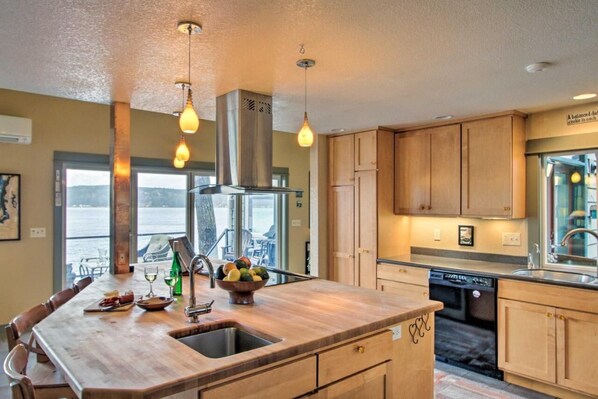 Enjoy cooking in this kitchen with a central island, sink, and range hood, offering a view of the outdoors.