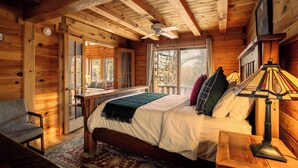 Une chambre dans une cabane en bois, avec un lit, une chaise, une table et un ventilateur de plafond.