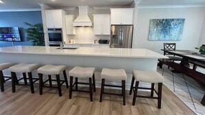 A modern kitchen with white cabinets, stainless steel appliances, and a large island with bar stools.