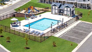 A swimming pool with sun loungers and a children's play area.