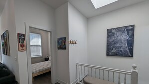 Ein Schlafzimmer mit einem Bett, einer Sitzbank, einem Fenster und einer Tür zu einem anderen Raum.