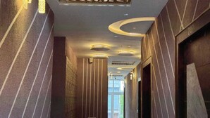 A hallway with striped walls, recessed lighting, and a door on the right. - Hotel Guruvayur Dham (Mathura)