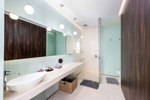 A modern bathroom with a large mirror, a white sink, and a glass shower enclosure.