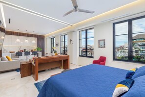 A modern hotel room with a large bed, a desk, and a balcony with a view of the city.