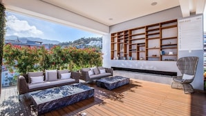 Ein moderner Außenbereich mit Holzterrasse, zwei Sofas und einer Sitzecke mit einem Sessel.