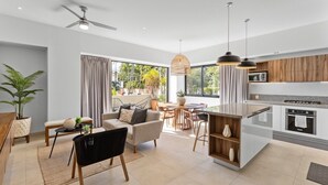 Eine moderne Küche mit Kochinsel, einem Essbereich mit Tisch und Stühlen sowie einem Wohnbereich mit Sofa und Couchtisch.